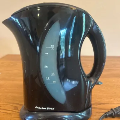 Sale Photo Thumbnail #253: This Proctor Silex Electric Tea Pot offers a convenient and efficient way to boil water quickly. Featuring a compact design in a sleek black color, it includes a clear water level indicator marked with measurements up to 1.5 liters for easy monitoring. Th