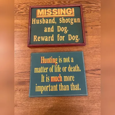 Sale Photo Thumbnail #154: This Hunters Wall Art set features two unique decorative signs with witty hunting-themed sayings. The first sign, framed in dark wood, reads 'MISSING! Husband, Shotgun and Dog, Reward for Dog,' adding a playful touch to any hunter's space. The second sign