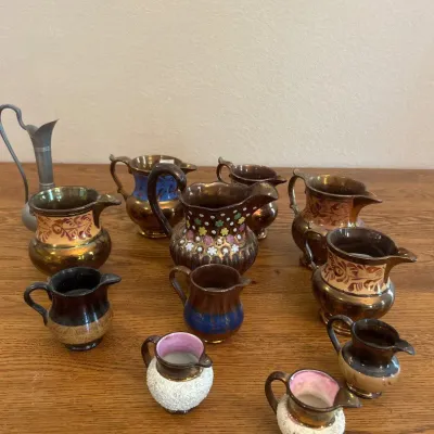 Sale Photo Thumbnail #27: A charming collection of assorted decorative hand-painted miniature pitchers featuring intricate designs and a variety of colors. This set includes small pitchers measuring approximately 2.5 to 3.5 inches in height, with distinctive textured white exterio