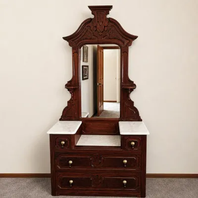 Sale Photo Thumbnail #9: Impressive late 19th-century Victorian dresser / marble-top washstand with tall mirror, featuring an elaborate carved and molded crest, richly figured wood drawer fronts, ornate brass-tone drop pulls with dark pendant knobs, and multiple white marble surf