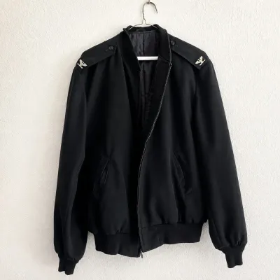 Sale Photo Thumbnail #58: This black military-style jacket features distinctive silver eagle emblems on both shoulder epaulets, adding a unique and bold detail to its design. Crafted in a long size 44, it offers a comfortable fit with ribbed cuffs and hem for a snug wear. The jack
