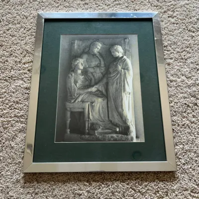 Sale Photo Thumbnail #97: Framed art print featuring a classical Greco-Roman style stone relief depicting three figures, with one seated figure flanked by two standing figures in draped garments. The detailed monochromatic image captures the sculptural texture and form of an ancie