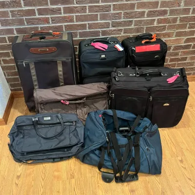 Sale Photo Thumbnail #225: This diverse collection features eight pieces of travel luggage and bags, each with unique carrying options including wheeled suitcases, garment bags, duffel bags, and briefcases. Highlighting various colors such as black, brown, dark blue, and tan, the s