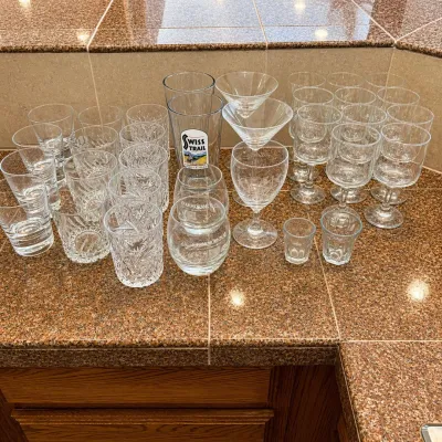 Sale Photo Thumbnail #293: This collection features a diverse assortment of 33 bar style glasses, ideal for any home bar or entertaining setting. The set includes various glass types such as highball, cocktail, whiskey, shot, and stemmed glasses, each exhibiting clear glass constru