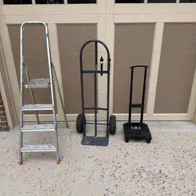 Sale Photo Thumbnail #209: This set includes a sturdy step ladder and two hand trucks, ideal for various moving and lifting tasks. The step ladder is made of durable metal with non-slip steps and orange safety caps on the feet for added stability. The hand trucks feature strong bla
