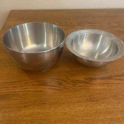 Sale Photo Thumbnail #260: This set features two durable metal bowls made from stainless steel, perfect for versatile kitchen use. The larger bowl measures approximately 8 inches in diameter with a height of about 4.5 inches, while the smaller bowl is around 9.5 inches in diameter 