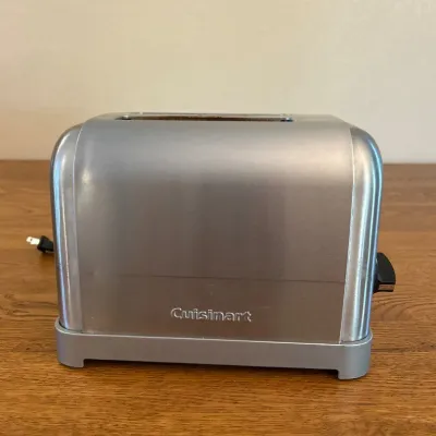 Sale Photo Thumbnail #249: This Cuisinart toaster features a sleek stainless steel exterior with a compact design measuring approximately 9 inches wide. It includes adjustable browning control with a rotary dial and a slide lever for easy operation. The toaster is designed for 2 sl