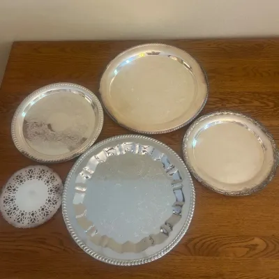 Sale Photo Thumbnail #147: This collection features a variety of silver plated platters, each showcasing unique designs and intricate detailing. The set includes platters of different sizes, with one measuring approximately 7 inches in diameter. One of these platters are unmarked w