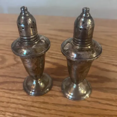 Sale Photo Thumbnail #17: Vintage pair of pedestal-form sterling silver salt and pepper shakers with removable perforated tops. Each features a tapered body, flared shoulder and round weighted foot. Undersides are marked “STERLING” and “WEIGHTED” surrounding a decorative m