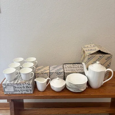 Sale Photo Thumbnail #142: This elegant Villeroy & Boch Arco Weiss tea set is crafted from fine bone china, featuring a pristine white finish that complements any table setting. The set includes 6 cups, 1 creamer, 1 sugar bowl, 8 plates measuring 6 inches each, and 1 coffee pot. Ea