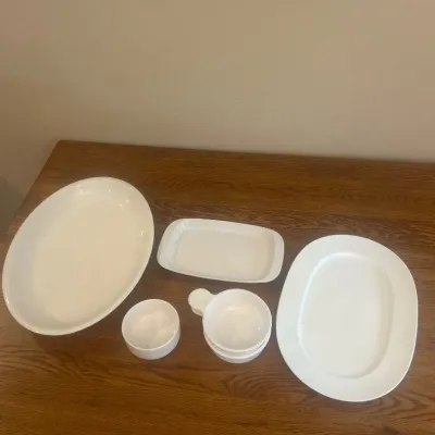 Sale Photo Thumbnail #262: This collection of white ceramic serving dishes includes multiple pieces designed for versatile use in your kitchen or dining area. Crafted from durable white ceramic, the set features bowls and plates of various shapes and sizes, including small handled 