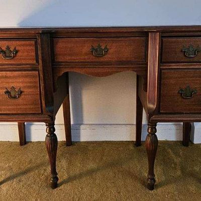 Sale Photo Thumbnail #4: This vintage mahogany Queen Anne style kneehole desk features a five-drawer configuration with ornate brass batwing pulls and fluted pillar accents. $700