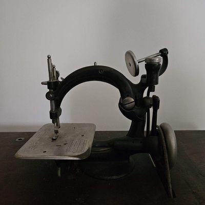 Sale Photo Thumbnail #37: This specific model is a highly collectible Willcox & Gibbs automatic chain stitch sewing machine, originally produced from the late 19th century into the early 20th century. It is easily recognized by its elegant "G-shaped" cast-iron frame. $500