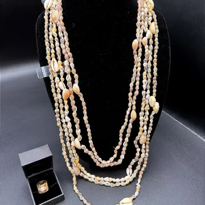 A Pink Stone Ring In A Gold-toned Setting And Five Shell Necklaces