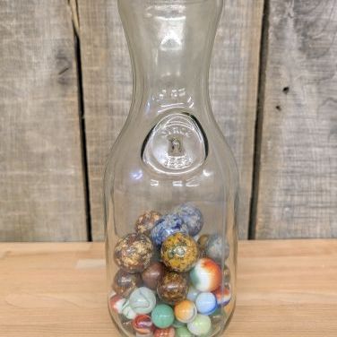Sale Photo Thumbnail #328: A Collection of Vintage Glass and Clay Marbles in an Embossed Paul Masson Carafe