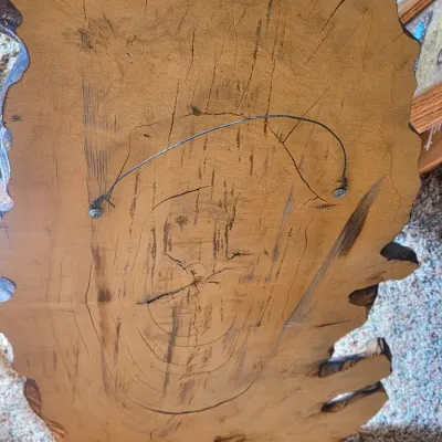 Rustic live-edge wood wall clock with a metal laser-engraved elk silhouette and a textured clock face with maple leaf detail