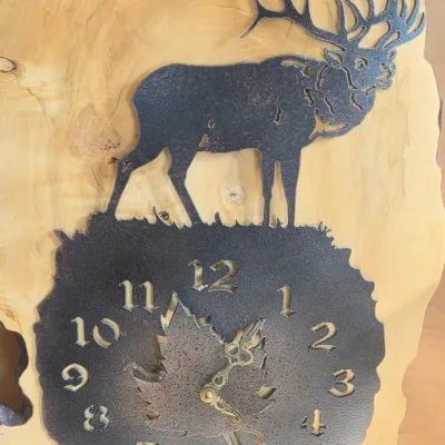 Rustic live-edge wood wall clock with a metal laser-engraved elk silhouette and a textured clock face with maple leaf detail