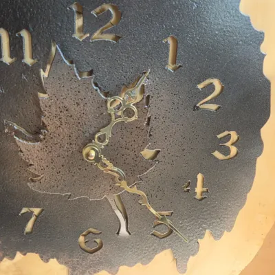 Rustic live-edge wood wall clock with a metal laser-engraved elk silhouette and a textured clock face with maple leaf detail