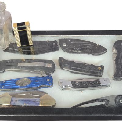 A Collection of Nine Folding Knives with a Vintage WIN Lighter and Antique Glass Bottle in a Display Case