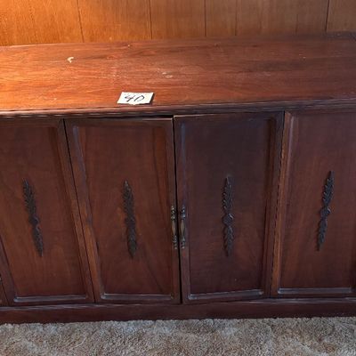 This vintage mid-century modern wooden stereo console features an integrated AM/FM radio and a top-loading record player turntable