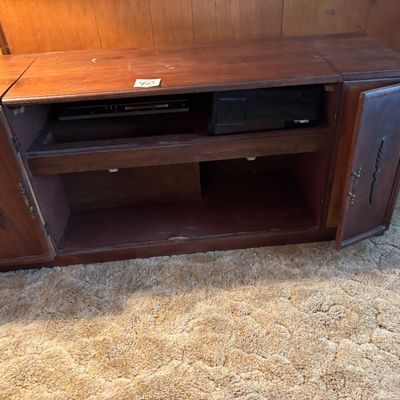 This vintage mid-century modern wooden stereo console features an integrated AM/FM radio and a top-loading record player turntable