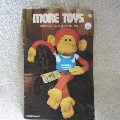 Sale Photo Thumbnail #21: Vintage Coats & Clark Book No. 304, 'More Toys' knitting and crochet pattern booklet. Features patterns for various toys, including the iconic sock monkey shown on the cover. In good vintage condition with some light wear and a sticker on the front cover.
