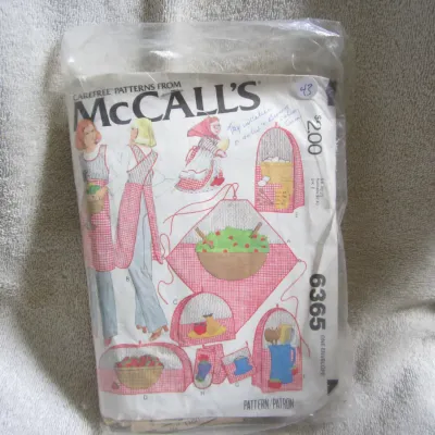 Sale Photo Thumbnail #44: Vintage Carefree Patterns from McCall's, pattern number 6365. Features designs for aprons and various kitchen accessories including food covers, pot holders, and appliance covers. The envelope shows some light wear and handwritten notes on the front. Appe