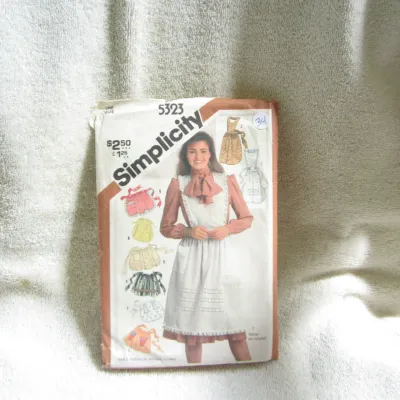Sale Photo Thumbnail #35: Vintage Simplicity sewing pattern number 5323 for aprons in one size. Features patterns for various apron styles including full aprons, half aprons, and pinafores. Envelope shows some wear, creasing, and minor markings consistent with age. Pattern pieces 