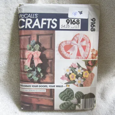 Sale Photo Thumbnail #49: Vintage McCall's Crafts sewing pattern number 9168, featuring 8 seasonal designs to decorate doors and walls. Designs include a holly wreath, heart, flowers, shamrock, and more. The envelope shows some wear, creasing, and has a retail sticker on the front