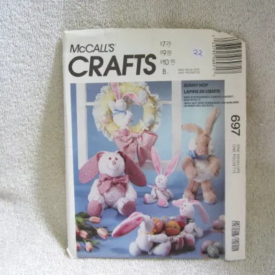 Sale Photo Thumbnail #23: Vintage McCall's Crafts sewing pattern number 697, titled 'Bunny Hop' ('Lapins en Liberte'). This pattern features designs for stuffed bunnies, a decorative wreath, a basket, and eggs. The envelope shows light wear and has a handwritten number '22' on the
