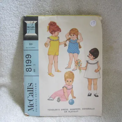 Sale Photo Thumbnail #18: Vintage McCall's printed sewing pattern 8199 for toddler's dress, rompers, coveralls, or playsuit. Size 2. The envelope shows light wear, minor creasing, and a small handwritten number on the front, but remains in good vintage condition.