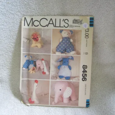 Sale Photo Thumbnail #19: Vintage McCall's sewing pattern number 8456 for creating various stuffed animals, including a lion, bear, elephant, goose, and rabbit. The envelope shows some wear, creasing, and handwritten price markings on the front. Includes original pattern pieces an