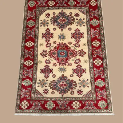 Ivory and red rug featuring colorful geometric and floral-inspired motifs with blue, gold, and rust accents and a bold red border.