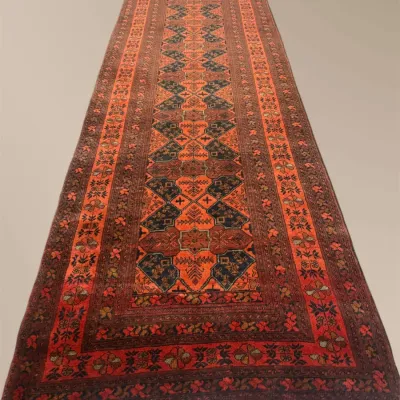 Rich orange, black, and red runner featuring bold repeating geometric motifs. A striking statement piece with warm saturated color.
