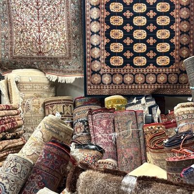 Extensive rug warehouse inventory with rolled and stacked rugs available in many sizes, patterns, colors, and traditional styles.