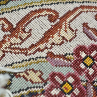 Detailed close-up of a handwoven rug featuring intricate geometric motifs and small colorful accents woven throughout the design.