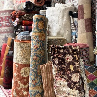 Warehouse selection of rolled handmade rugs featuring floral, medallion, traditional, and decorative patterns in a variety of rich colors.