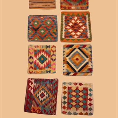Colorful collection of small geometric woven rugs featuring diamond, checkerboard, and tribal-inspired patterns in vibrant red, blue,...