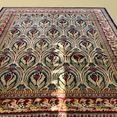 Blue and ivory rug featuring a flowing repeating decorative pattern with a colorful floral-inspired border along the edge.