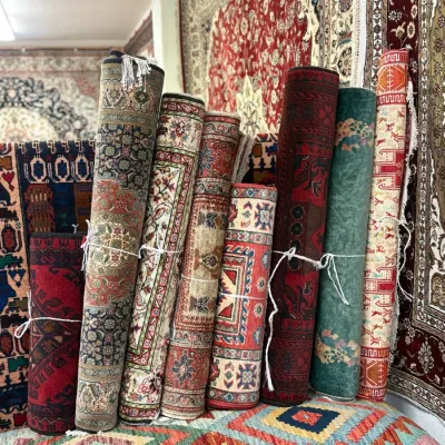 Colorful assortment of rolled handmade rugs featuring intricate patterns, rich colors, and a variety of traditional and contemporary...