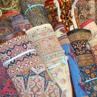 Colorful assortment of handmade rugs featuring intricate traditional motifs, decorative borders, and vibrant blue, pink, orange, ivory,...