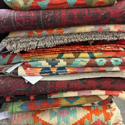 Stack of beautiful and colorful Kilim flatweave rugs.