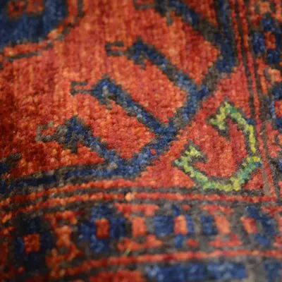 Close-up of a vibrant textured rug featuring saturated orange, blue, green, and red geometric detailing.