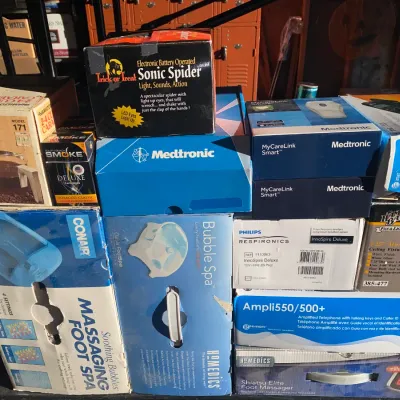 A collection of boxed household items, electronics, and novelty goods, including foot spas, small medical devices, an AT&T telephone,...