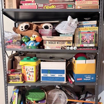 Assorted Vintage Board Games and Collectible Toys Collection on Metal Shelving Unit