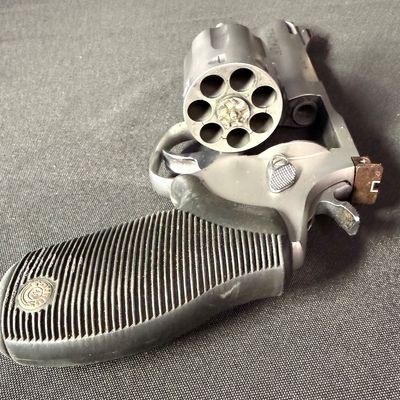 Sale Photo Thumbnail #414: This is a very nice matte stainless steel seven-shot, double action revolver. It fires .357 mag or .38 special (+P) ammo. It has a four-inch barrel, and soft rubber grips. It has a fixed front ramp and adjustable rear sight. It has a ported barrel to redu