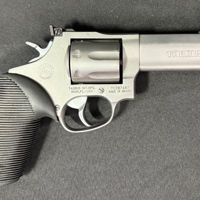 Sale Photo Thumbnail #411: This is a very nice matte stainless steel seven-shot, double action revolver. It fires .357 mag or .38 special (+P) ammo. It has a four-inch barrel, and soft rubber grips. It has a fixed front ramp and adjustable rear sight. It has a ported barrel to redu