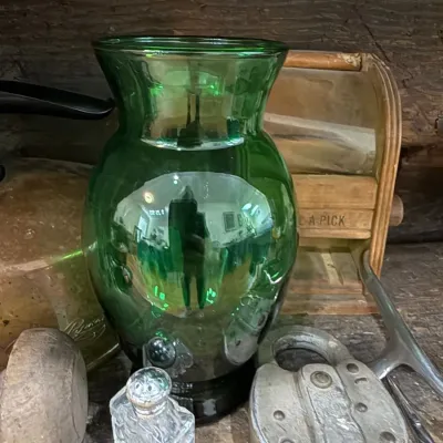 Green glass vase on primitive wood shelf
