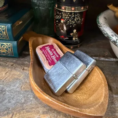 Pair of vintage chrome pocket lighters in wood dish