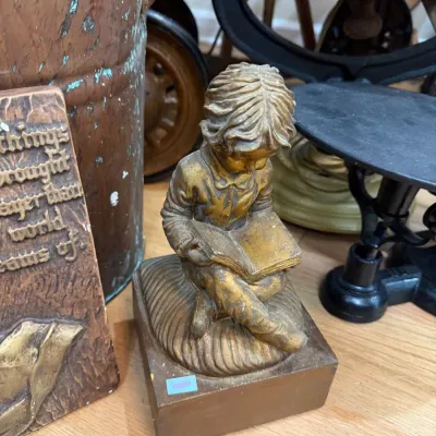 Gilt figurine of child reading on wood base